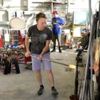 Hartwick College alumnus blowing glass in the studio of Anderson Center for the Arts