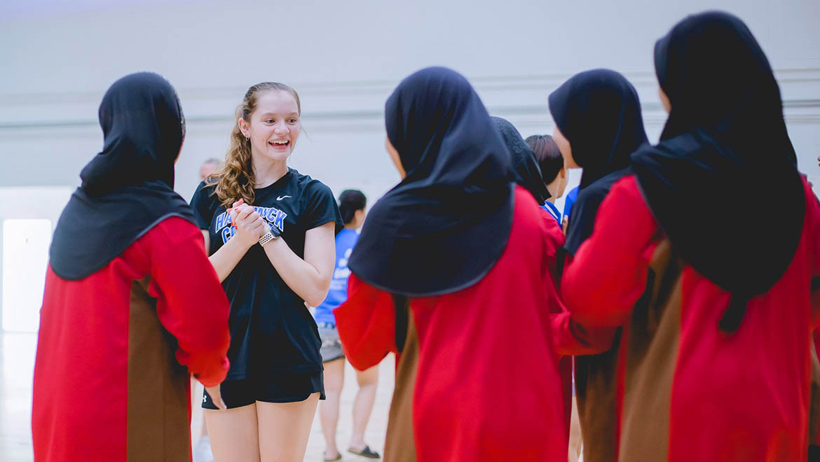 Hartwick College student in the U.S. State Department’s Bureau of Education and Cultural Affairs Sports Diplomacy Division at volleyball tournament talking with other students and volleyball players