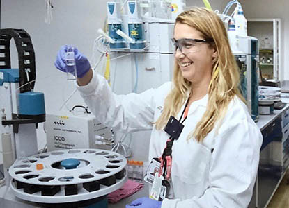 Hartwick alumna Diana Sardelis Simcox '17 in laboratory looking at samples