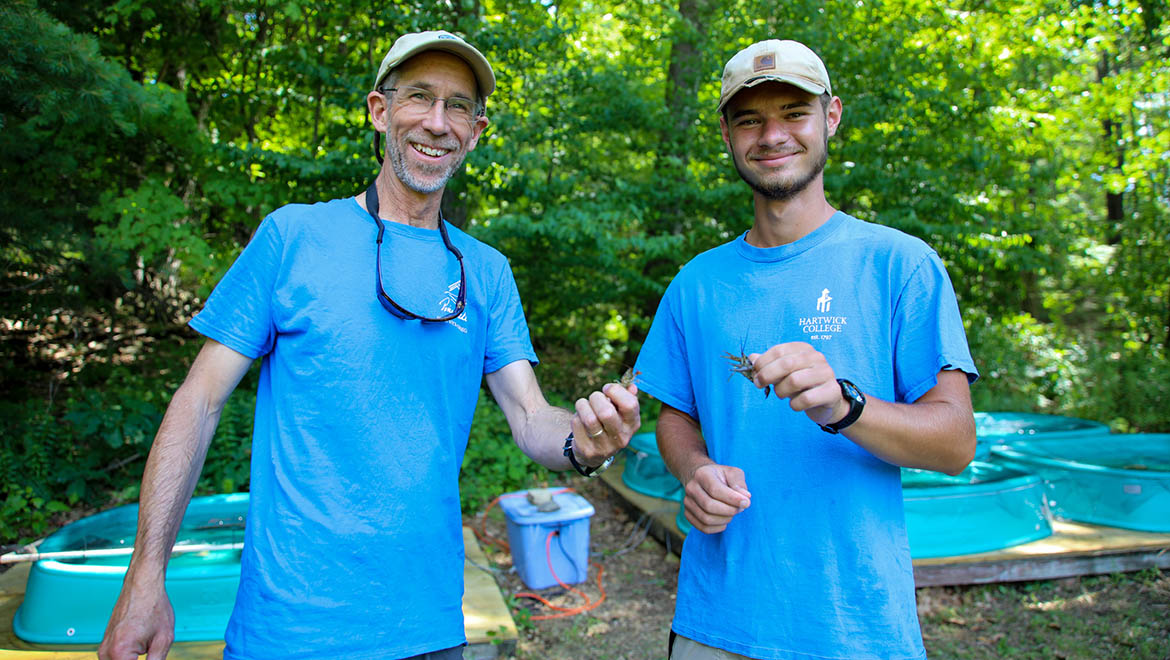 Hartwick College faculty member and student researcher with crayfish at Pine Lake