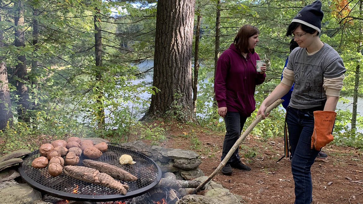 Hartwick College students at fire during outdoor cooking ceramics class