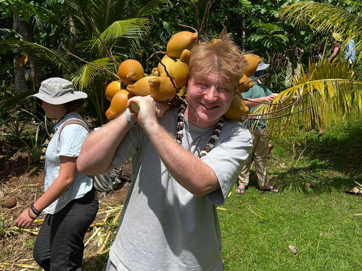 Hartwick student carrying fruit in Micronesia